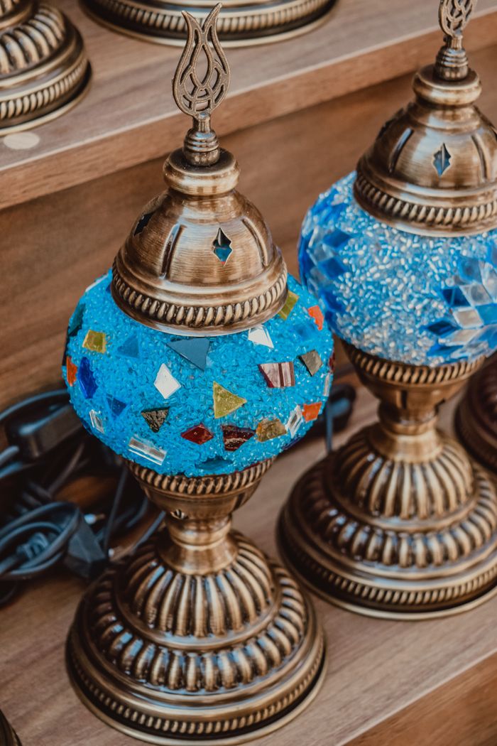 Decorative mosaic lamps with vibrant blue and multicolor designs on a display shelf.