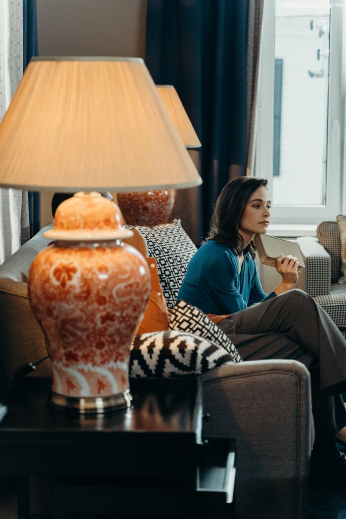 A woman in a blue sweater enjoys a cozy moment on a sofa in a stylishly decorated living room.