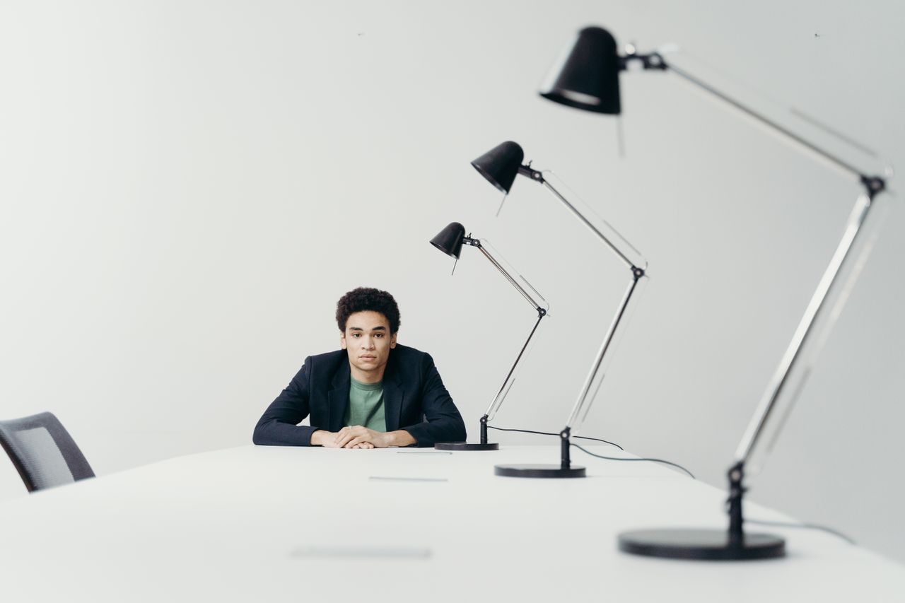 Crafting Captivating Headlines: Your awesome post title goes here Young professional man seated at a long desk in a modern office with multiple lamps.